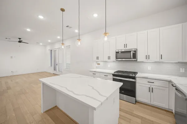 a kitchen with stainless steel appliances kitchen island a sink a stove a center island and a cabinets