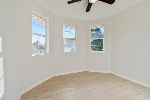 an empty room with chandelier fan and windows