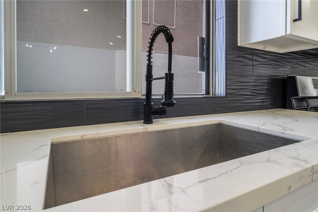 9171 West Viking Road Las Vegas, NV 89147 - Photo 21 of 43 A modern kitchen boasts sleek countertops, a large sink, and a stylish black faucet.