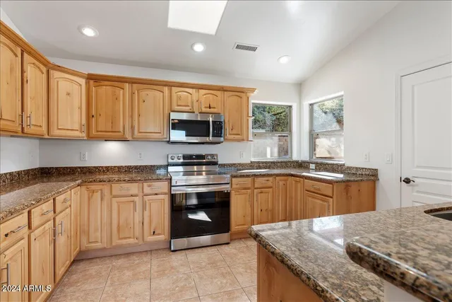 a kitchen with stainless steel appliances granite countertop a sink and a refrigerator