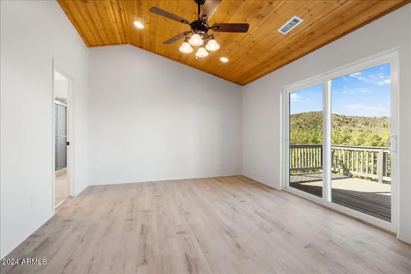 a view of an empty room with window and wooden floor