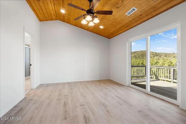 a view of an empty room with window and wooden floor