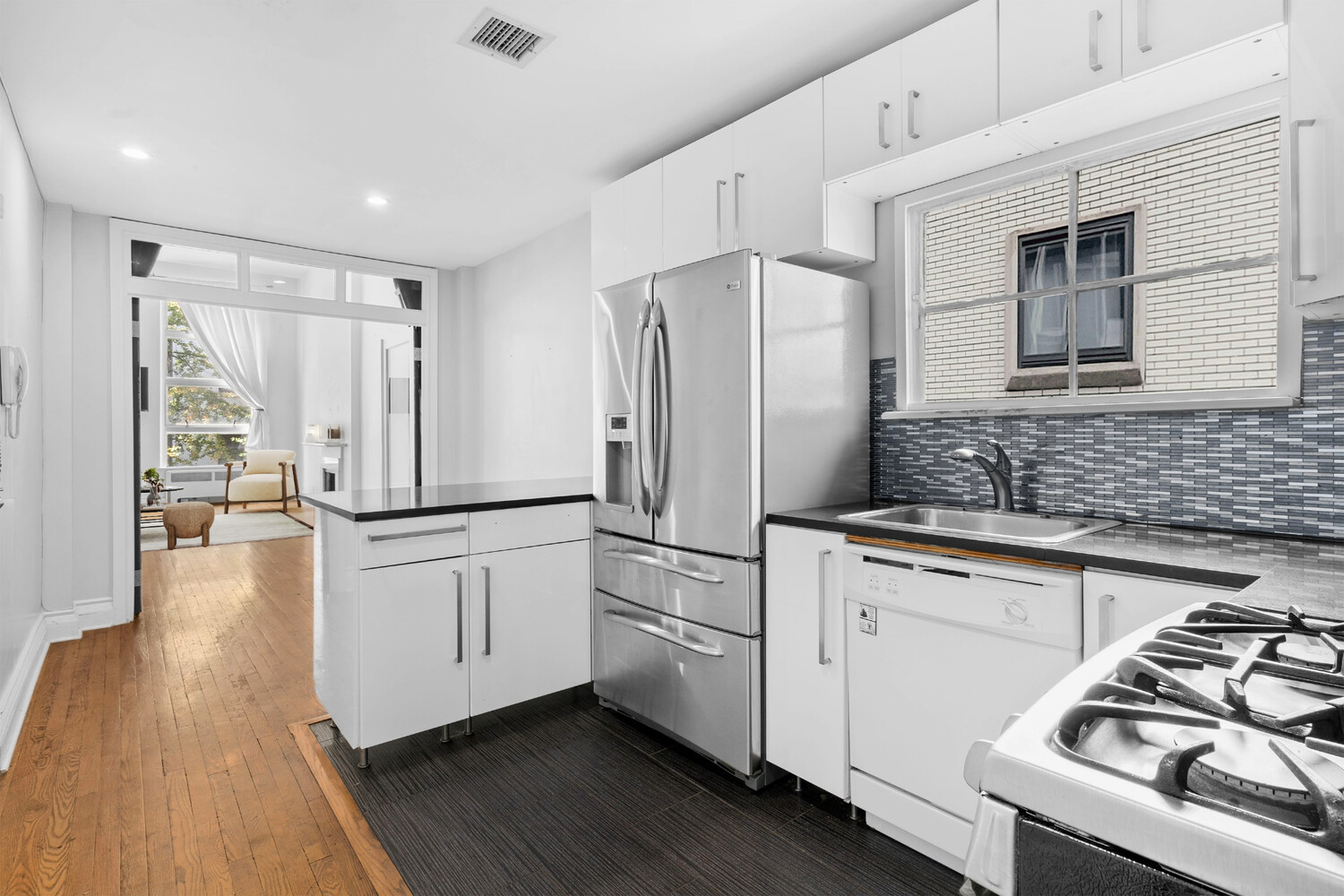 33 West 9th Street Manhattan, NY 10011 - Photo 7 of 15 a kitchen with stainless steel appliances a refrigerator a stove a sink and white cabinets with wooden floor