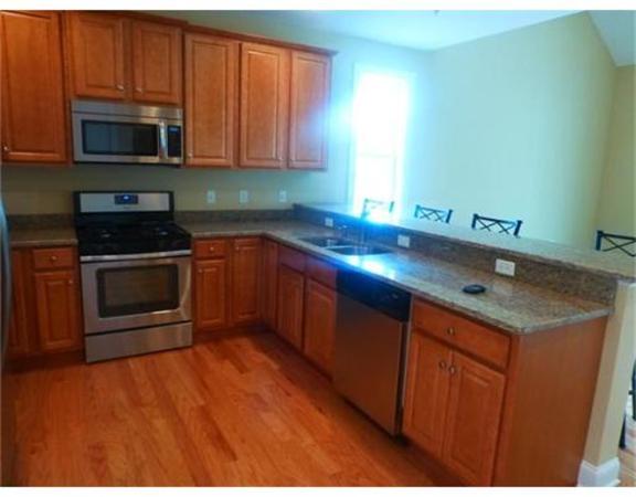 53 Baldwin Road, Unit 1402 Billerica, MA 01821 - Photo 9 of 30 a kitchen with stainless steel appliances granite countertop a sink a stove a microwave and wooden cabinets