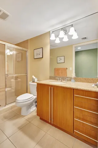 a bathroom with a granite countertop toilet sink and mirror