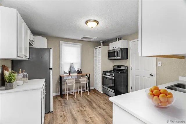 a kitchen with stainless steel appliances granite countertop a stove top oven a sink a dining table and chairs with wooden floor