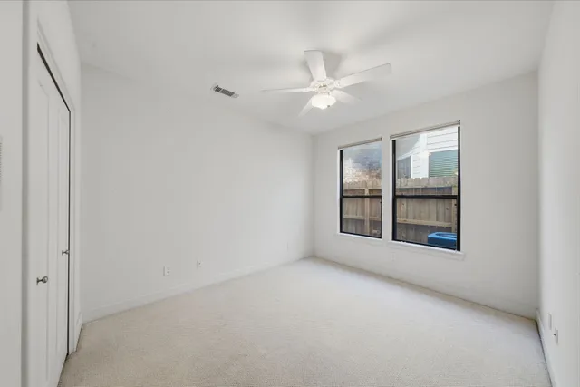 an empty room with a window and ceiling fan