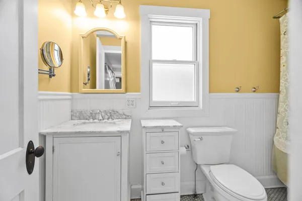 a bathroom with a toilet sink vanity and mirror