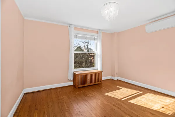 a view of an empty room with a window and wooden floor