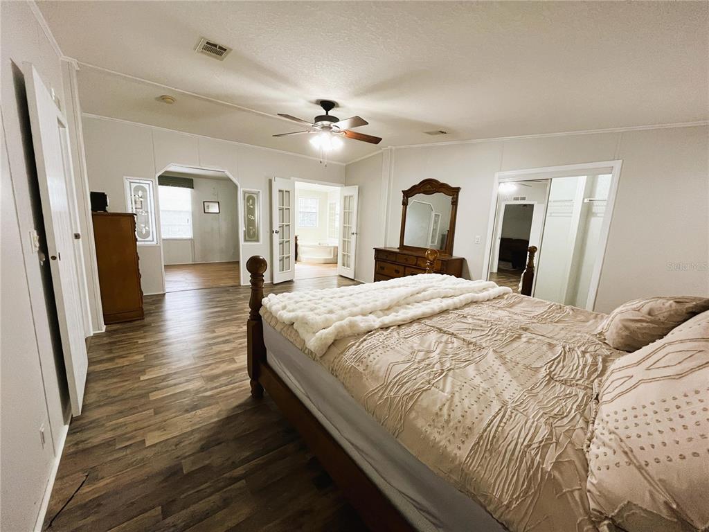 7750 156th Terrace Live Oak, FL 32060 - Photo 17 of 41 a spacious bedroom with a large bed and a chandelier