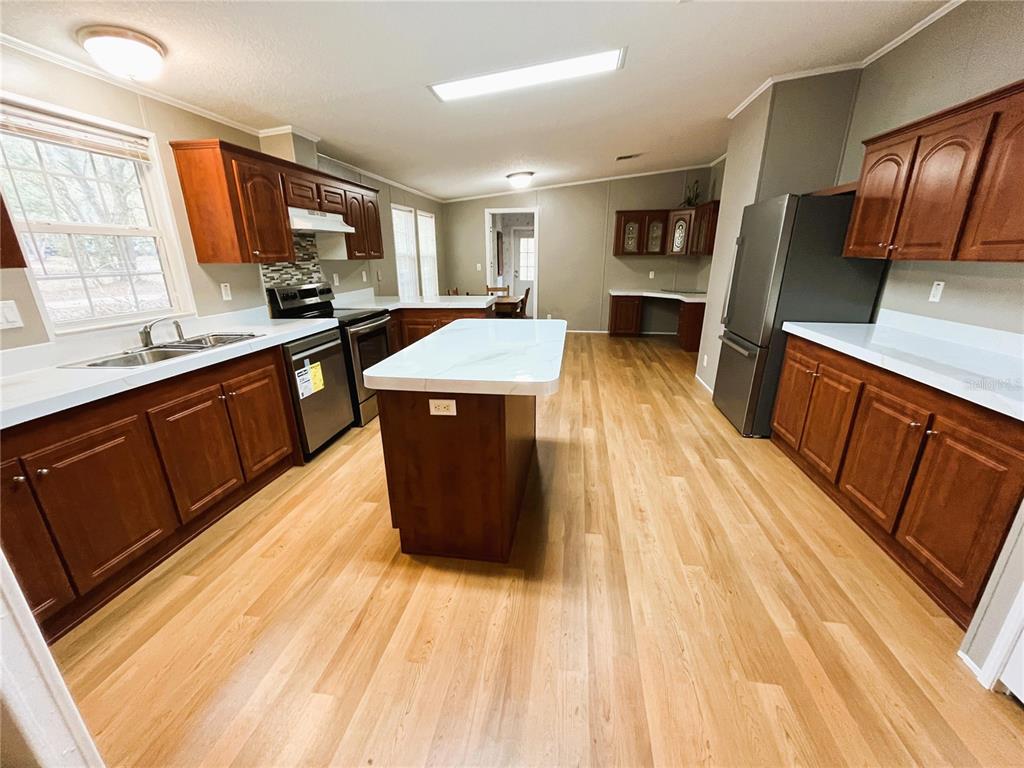 7750 156th Terrace Live Oak, FL 32060 - Photo 9 of 41 a large kitchen with stainless steel appliances wooden floors and wooden cabinets