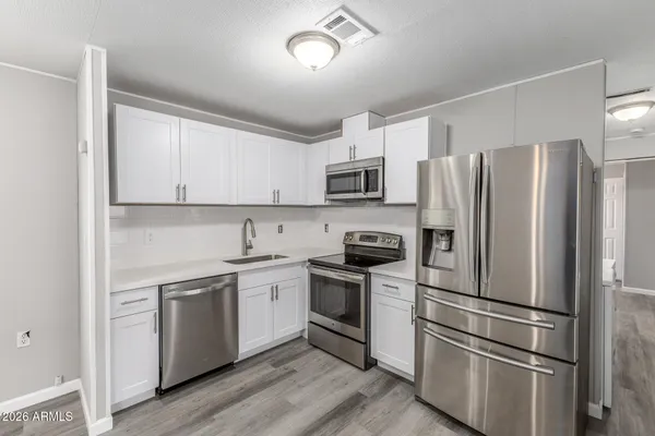a kitchen with granite countertop a refrigerator stove and sink