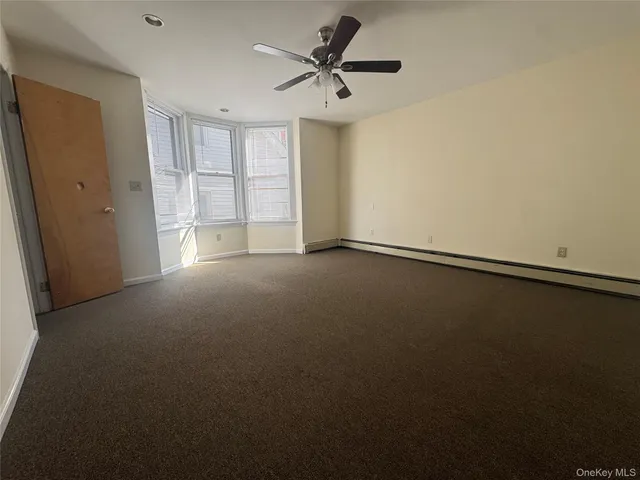 an empty room with a window and a ceiling fan
