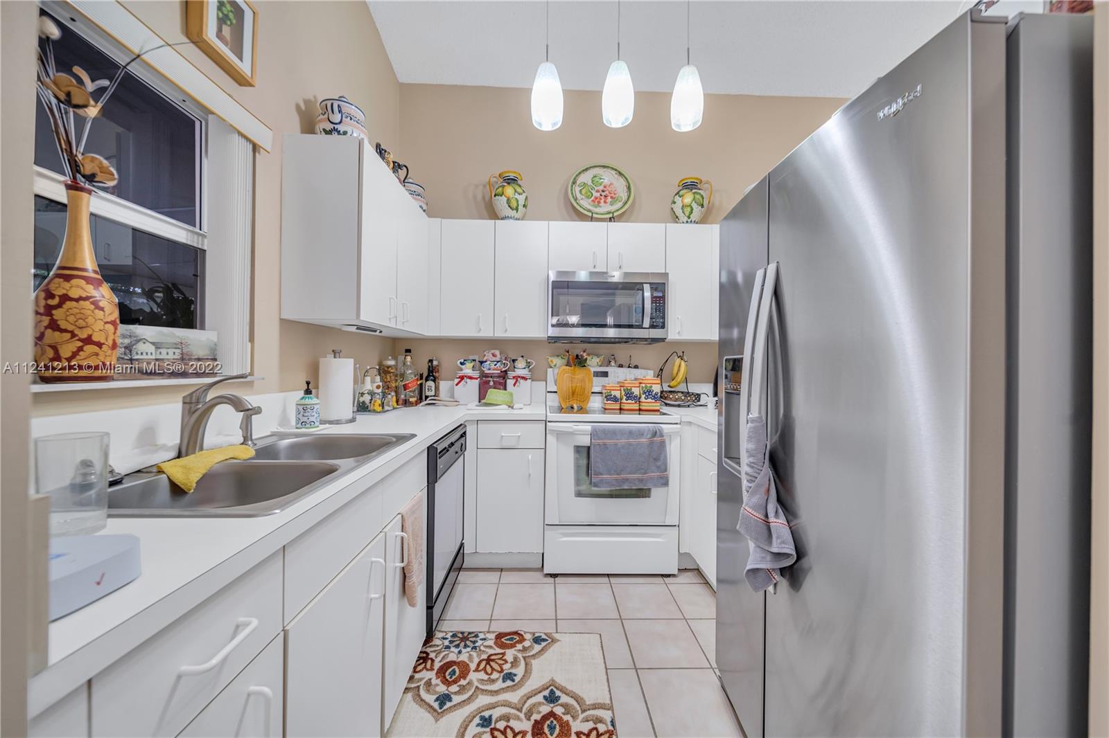 14202 Southwest 151st Court Miami, FL 33196 - Photo 6 of 23 a kitchen with a sink a refrigerator and cabinets