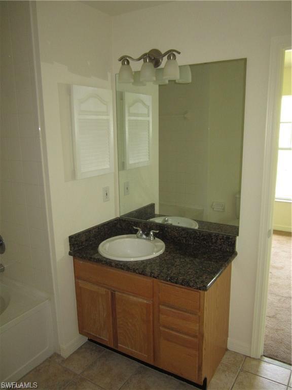 7960 Preserve Circle, Unit 634 Naples, FL 34119 - Photo 8 of 12 a bathroom with a granite countertop sink and a mirror