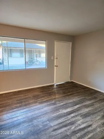 a view of an empty room with wooden floor and a window