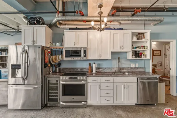 a kitchen with stainless steel appliances granite countertop a refrigerator a stove and white cabinets