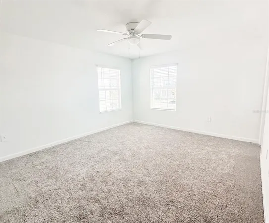 an empty room with a window and a ceiling fan