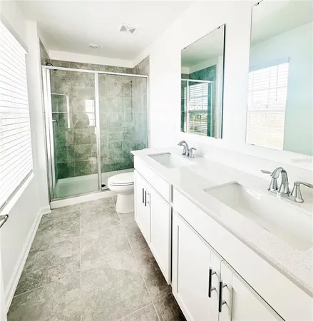 a spacious bathroom with a double vanity sink toilet mirror and next to a window