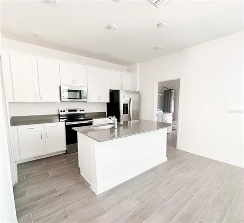 a large white kitchen with wooden floor