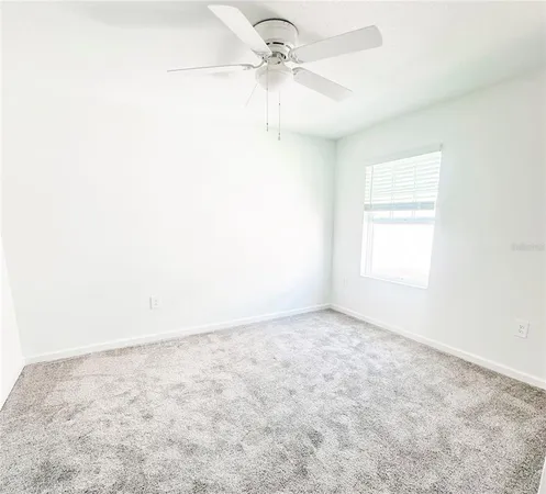 an empty room with a window and a ceiling fan