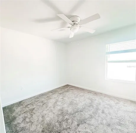 an empty room with a window and a fan