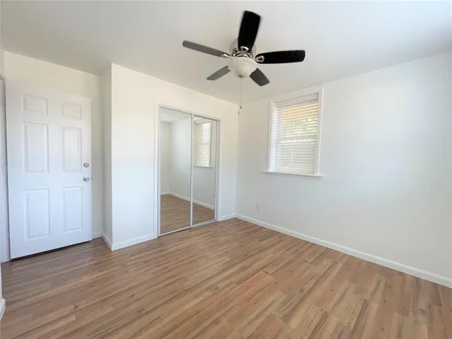 an empty room with wooden floor fan and windows
