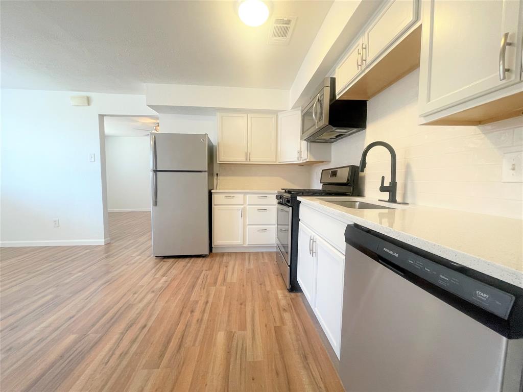2309 Wesley Street, Unit B Greenville, TX 75401 - Photo 6 of 27 a kitchen with a sink a refrigerator and a stove top oven