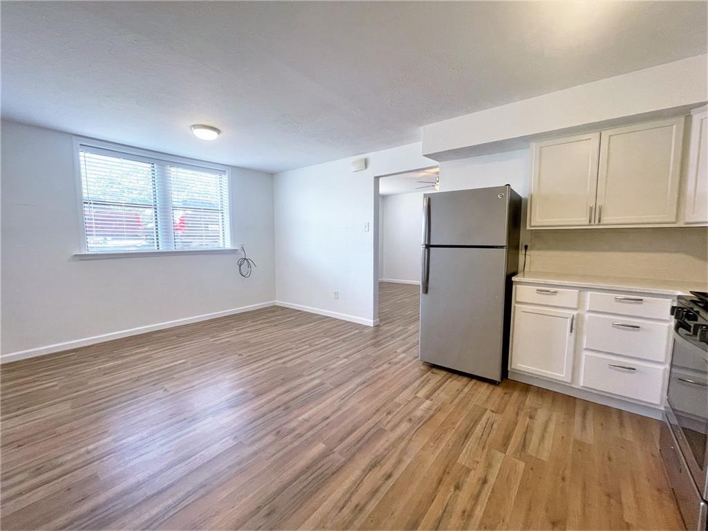 2309 Wesley Street, Unit B Greenville, TX 75401 - Photo 7 of 27 a view of a kitchen with a white refrigerator freezer a stove top oven a refrigerator and white cabinets with wooden floor