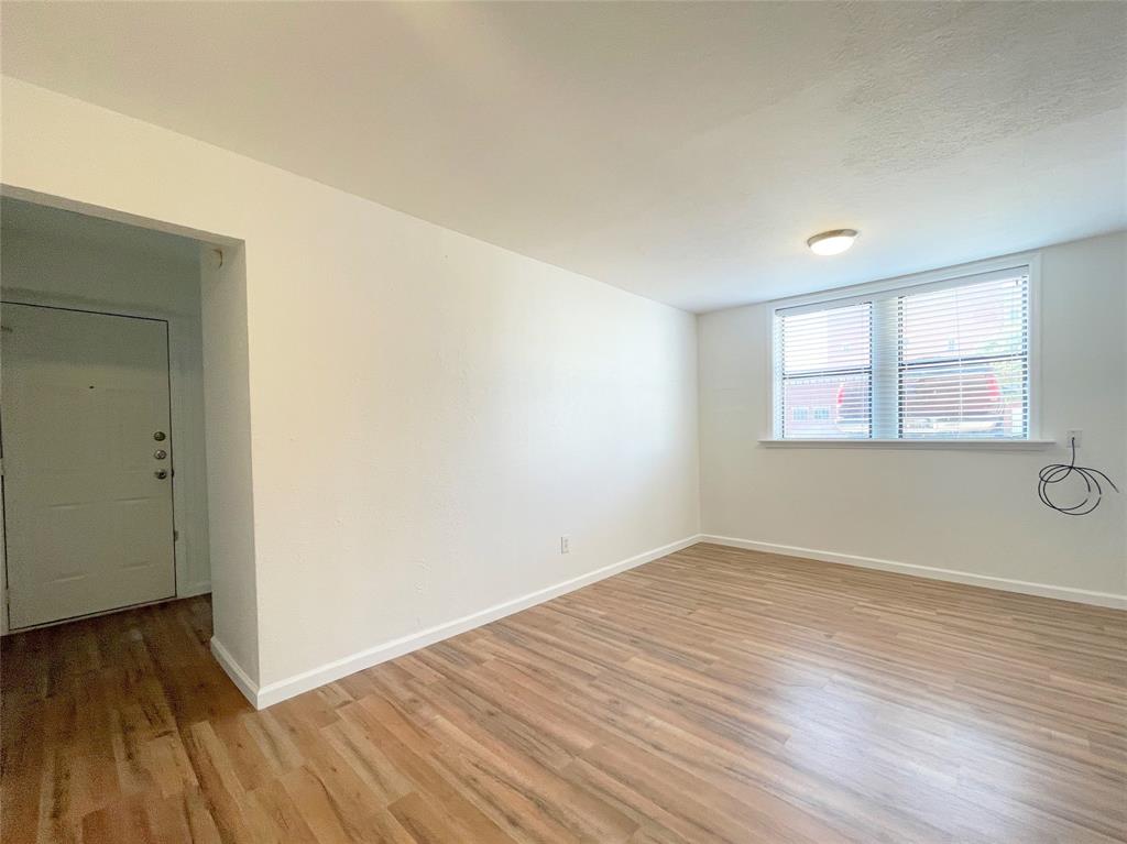 2309 Wesley Street, Unit B Greenville, TX 75401 - Photo 9 of 27 a view of an empty room with wooden floor and a window