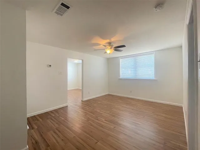 an empty room with wooden floor and ceiling fan