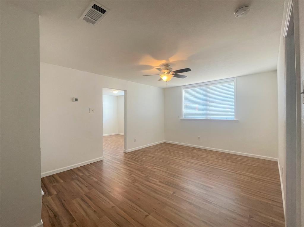 2309 Wesley Street, Unit B Greenville, TX 75401 - Photo 10 of 27 an empty room with wooden floor chandelier fan and windows