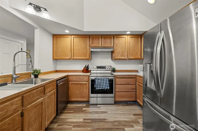 a kitchen with stainless steel appliances granite countertop a stove a sink and a refrigerator