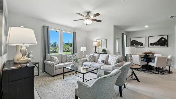a kitchen with stainless steel appliances kitchen island granite countertop a dining table chairs and a refrigerator