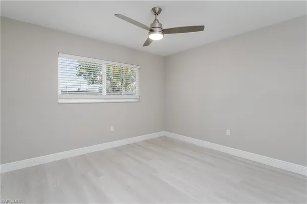 an empty room with a window and a fan