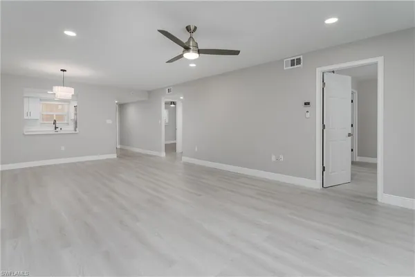 an empty room with wooden floor ceiling fan and windows
