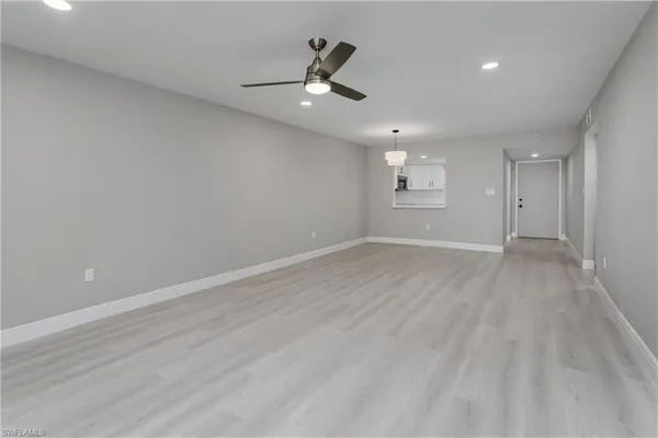 an empty room with wooden floor and ceiling fan