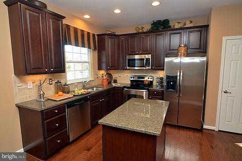 7332 Windsor Mill Road Baltimore, MD 21244 - Photo 5 of 19 a kitchen with kitchen island granite countertop wooden cabinets stainless steel appliances a window and a sink