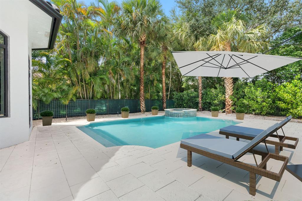 17935 Monte Vista Drive Boca Raton, FL 33496 - Photo 58 of 60 a backyard of a house with table and chairs under an umbrella