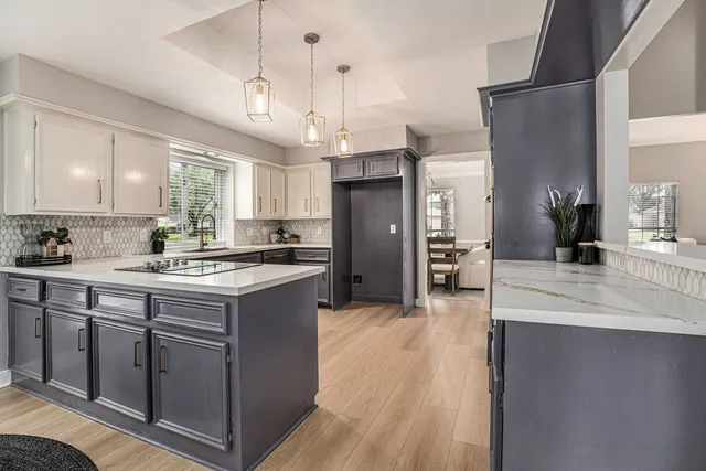 a large kitchen with stainless steel appliances kitchen island granite countertop a refrigerator a sink dishwasher a stove and white cabinets with wooden floor