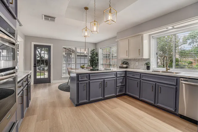 a kitchen with stainless steel appliances granite countertop a stove top oven a sink dishwasher a dining table and chairs with wooden floor