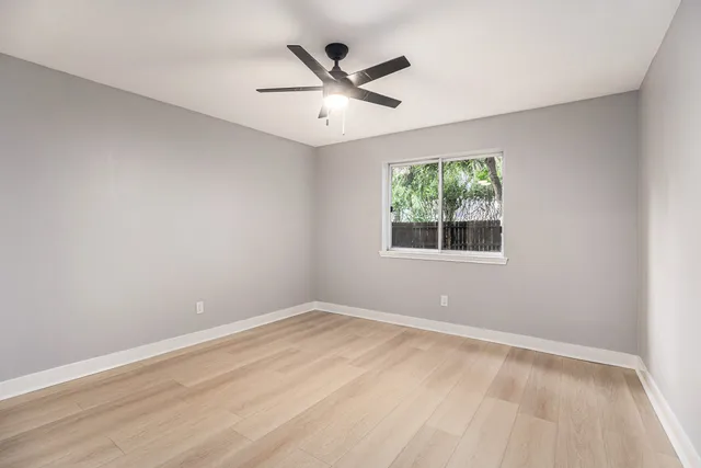 an empty room with window and ceiling fan