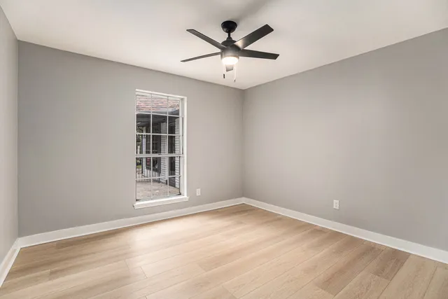 an empty room with wooden floor and ceiling fan