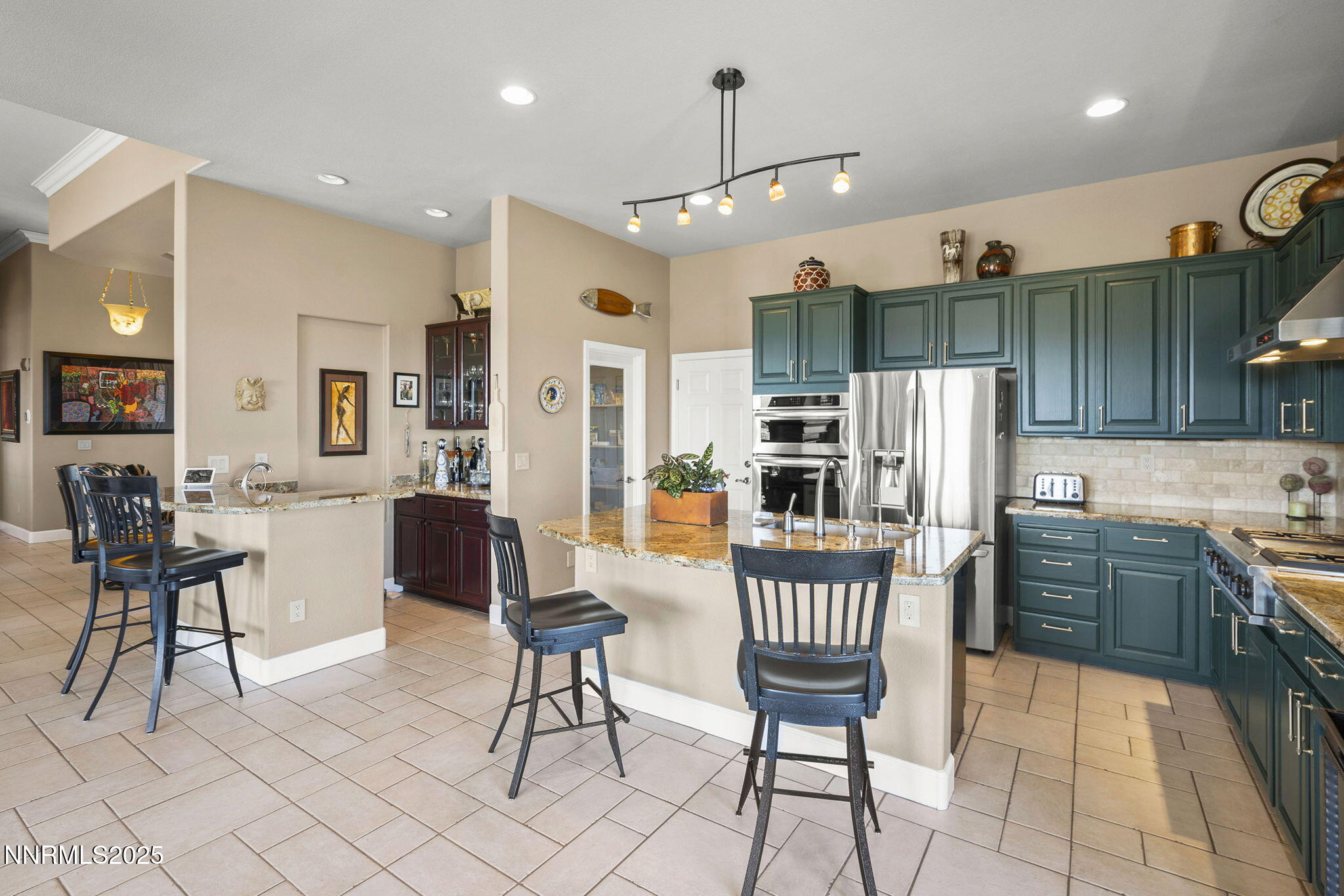 2698 Wind Feather Trail Reno, NV 89511 - Photo 13 of 44 a kitchen with stainless steel appliances kitchen island granite countertop a table chairs and a refrigerator