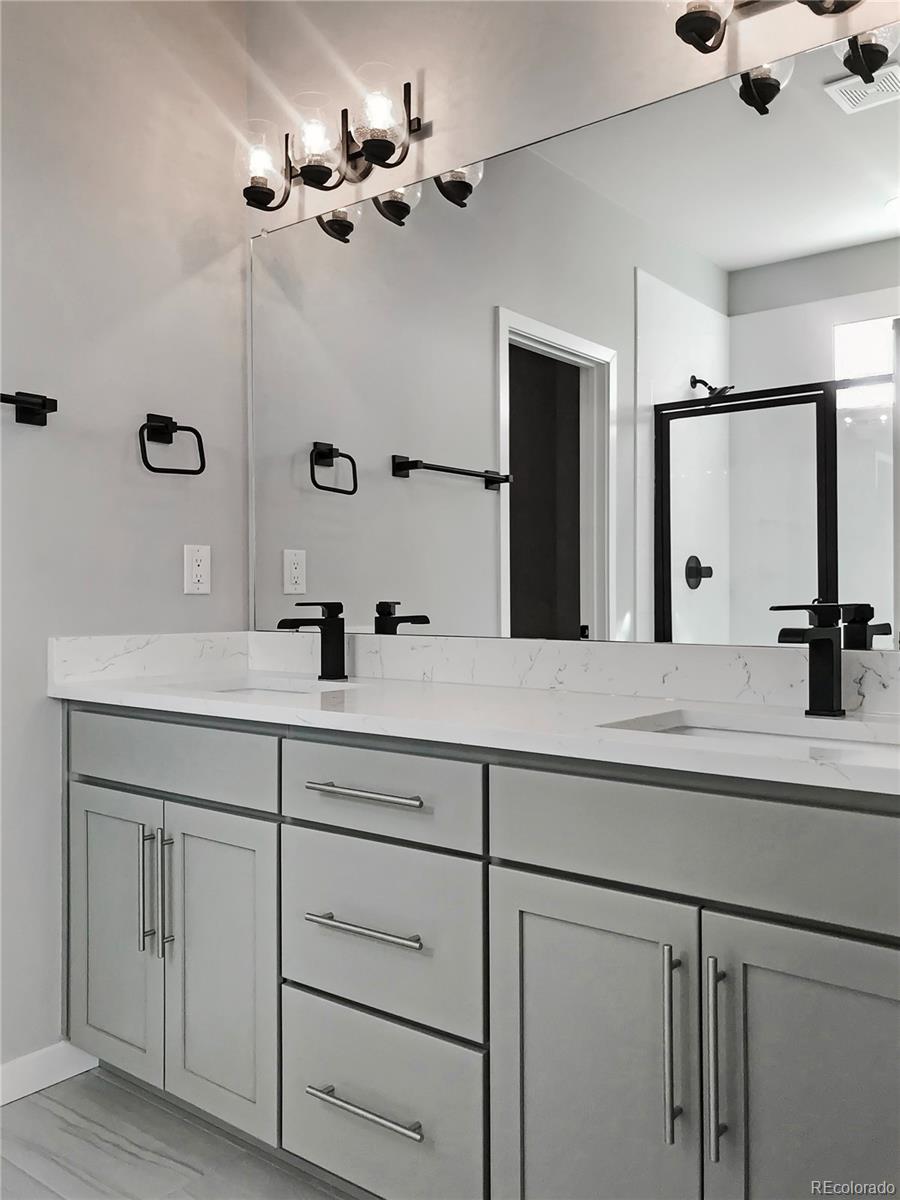 6767 South Tempe Court Aurora, CO 80016 - Photo 12 of 25 a bathroom with a double vanity sink a mirror and shower
