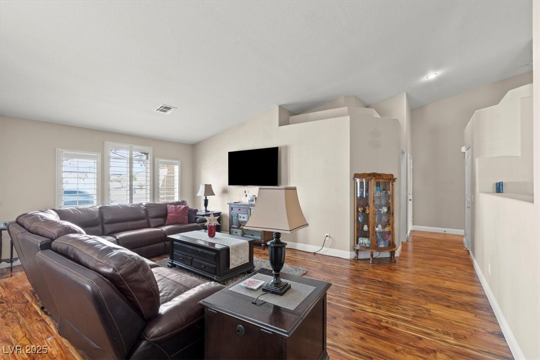 9031 West Viking Road Las Vegas, NV 89147 - Photo 5 of 33 Living room featuring visible vents, baseboards, lofted ceiling, and wood finished floors