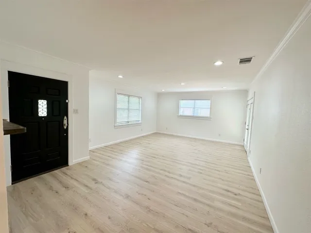 a view of an empty room with window and wooden floor