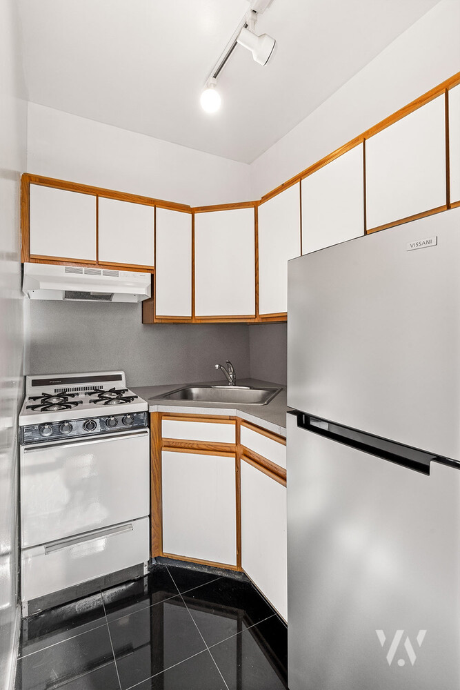 112 West 72nd Street, Unit 12E Manhattan, NY 10023 - Photo 5 of 11 a kitchen with stainless steel appliances granite countertop a refrigerator and a stove