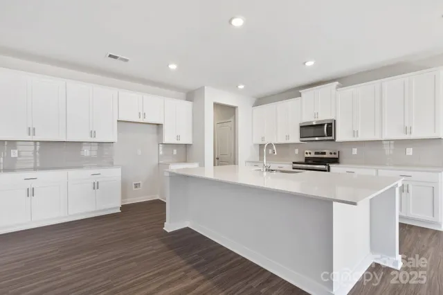 a kitchen with stainless steel appliances a refrigerator sink and white cabinets