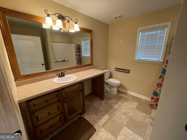 a bathroom with a sink a toilet a mirror and shower